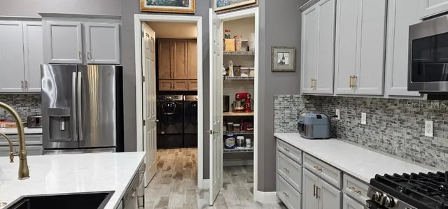 a kitchen with stainless steel appliances kitchen island granite countertop a table chairs sink and cabinets