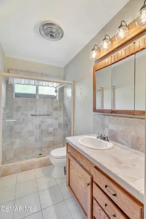 a bathroom with a granite countertop sink a toilet a mirror and shower
