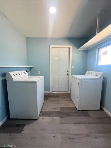 a utility room with a washer dryer with white wooden cabinets