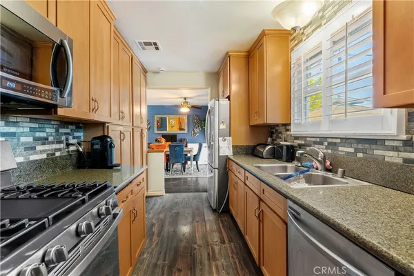 a kitchen with stainless steel appliances granite countertop a stove a sink and a microwave