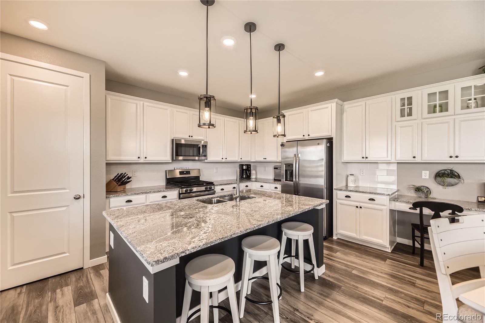 1182 Williams Loop Elizabeth, CO 80107 - Photo 12 of 42 a kitchen with kitchen island a refrigerator a stove a sink and chairs