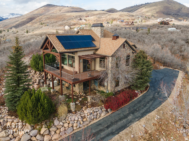 6679 North Durfee Creek Road Eden, UT 84310 - Photo 1 of 1 View of front of house with a chimney, stone siding, solar panels, and a deck with mountain view