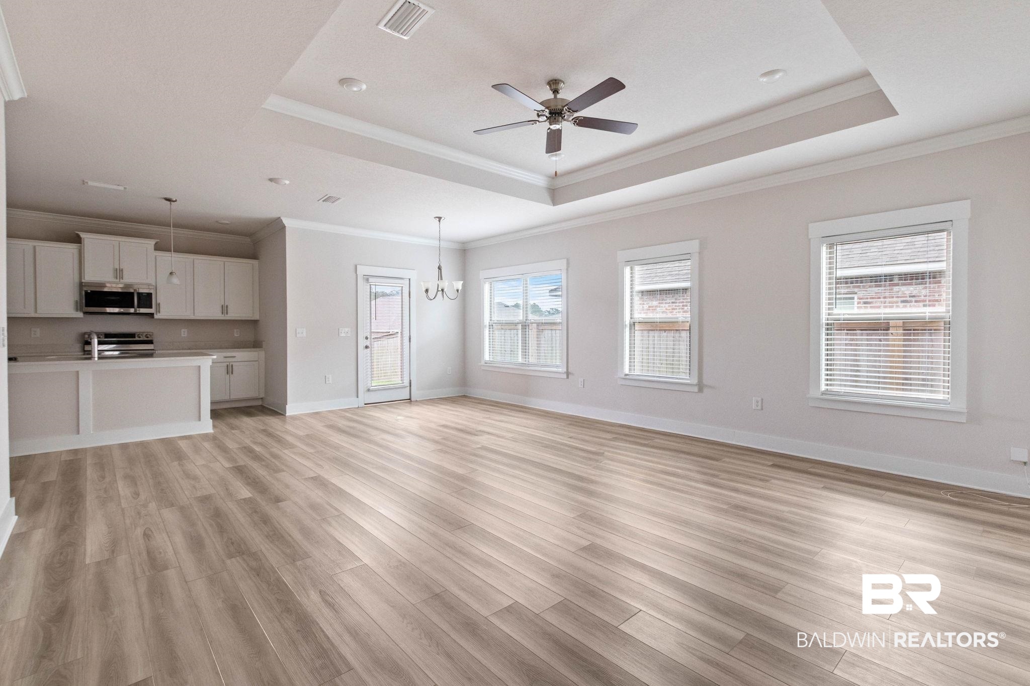 1710 Grouse Street Foley, AL 36535 - Photo 15 of 76 Open-concept living space featuring wood-finish flooring, a tray ceiling with a ceiling fan, and multiple windows with blinds