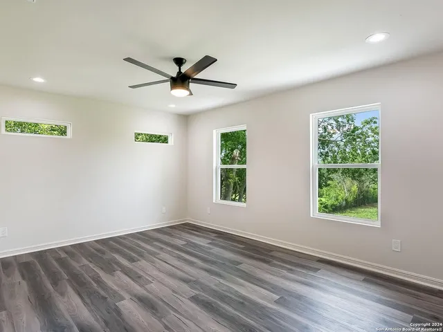 a view of empty room with wooden floor and fan
