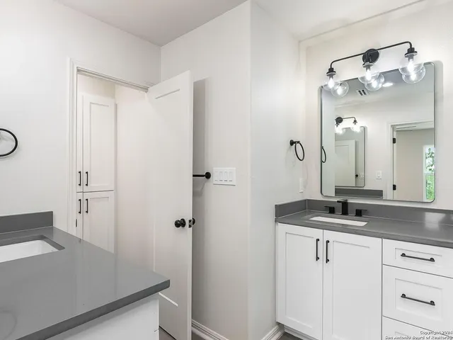 a bathroom with a granite countertop sink a mirror and shower
