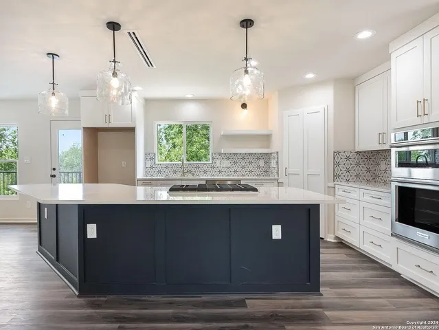 a kitchen with kitchen island granite countertop a sink a stove and cabinets