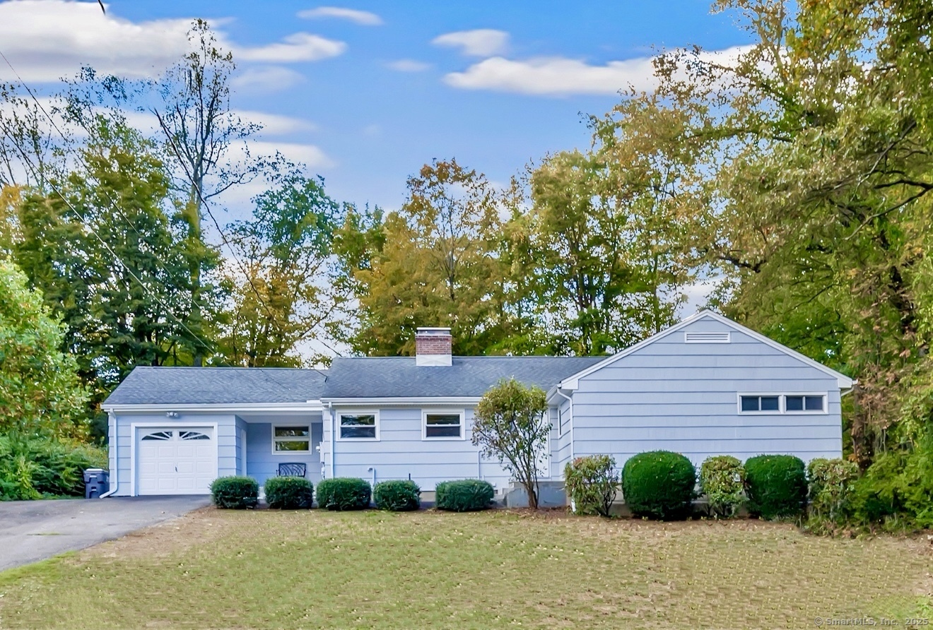 a front view of a house with a yard and large tree