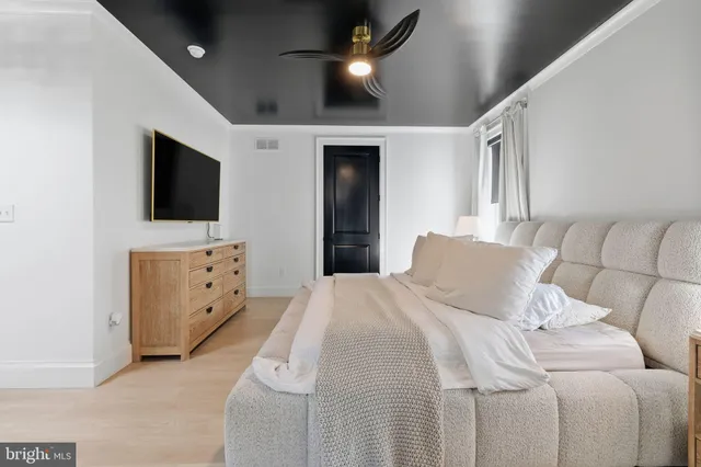 a bedroom with a bed and a flat tv screen on dresser