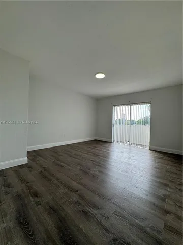 a view of an empty room with wooden floor and glass door