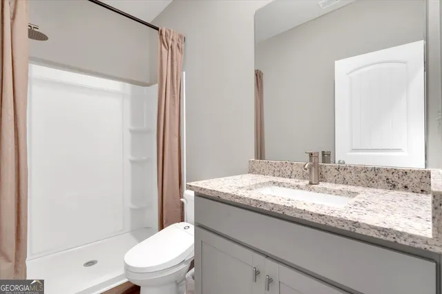 a bathroom with a granite countertop sink toilet mirror and a shower