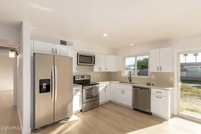 a kitchen with a sink a refrigerator a counter top space and cabinets