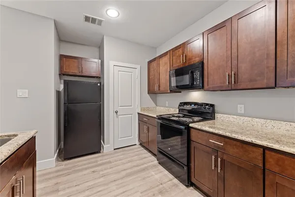 a kitchen with granite countertop wooden cabinets and a stove top oven
