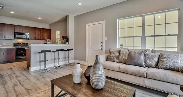 a living room with furniture kitchen and a wooden floor