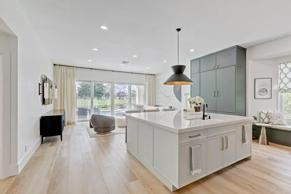 a large white kitchen with a large window a sink and stainless steel appliances