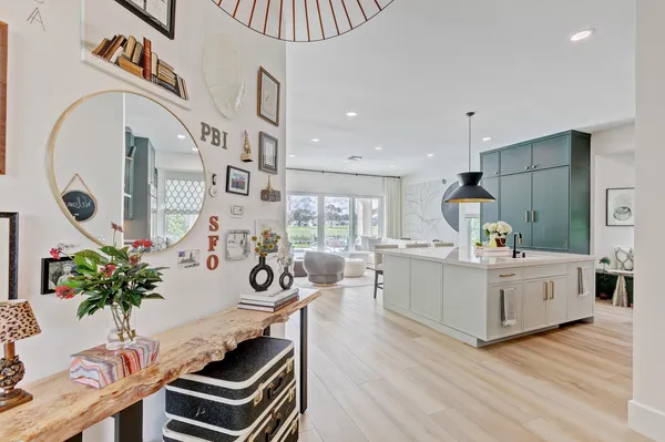 a large white kitchen with stainless steel appliances granite countertop a stove a sink a refrigerator and a dining table with wooden floor