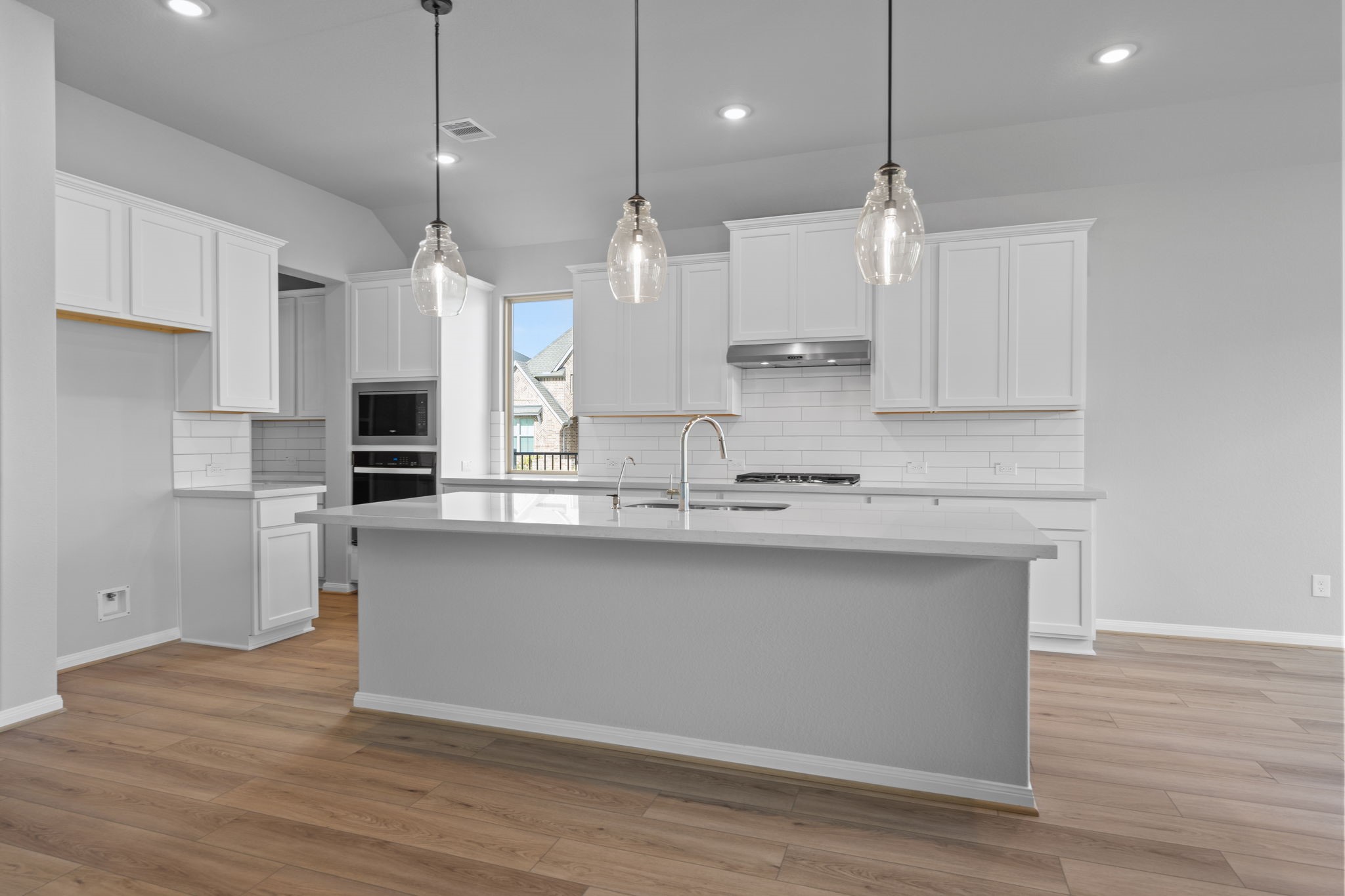 10726 Rattlebox Court Cypress, TX 77433 - Photo 4 of 36 a large kitchen with granite countertop a stove a sink and white cabinets with wooden floor