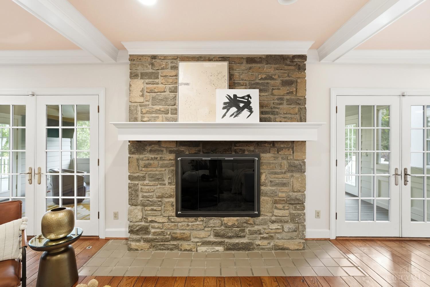 2780 Walsh Road Cincinnati, OH 45208 - Photo 7 of 77 This warm and inviting family room is designed for everyday living and effortless entertaining—anchored by a striking stone fireplace and framed by rich hardwood floors and classic millwork. The generously scaled layout offers multiple seating areas, seamless flow to adjacent spaces and French doors that invite in natural light while opening to outdoor living. Custom built-ins add both function and charm, completing this comfortable yet refined gathering space.