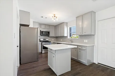 a kitchen with kitchen island granite countertop a sink cabinets and stainless steel appliances