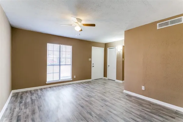 a view of an empty room with wooden floor and a window
