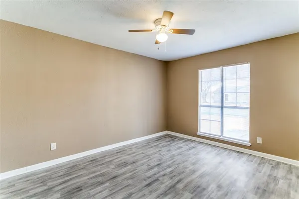 an empty room with a window and a ceiling fan