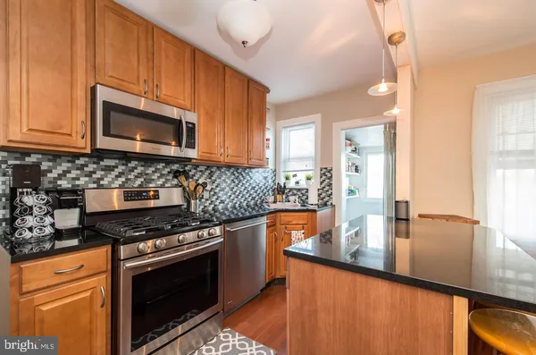 a kitchen with stainless steel appliances granite countertop a stove a sink and a microwave