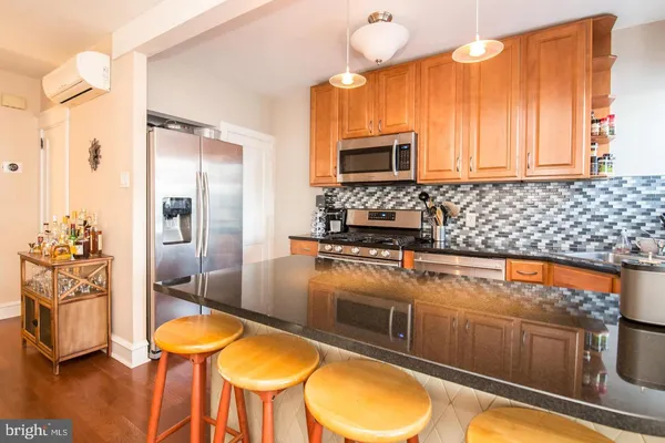 a kitchen with stainless steel appliances a stove a sink and a refrigerator with wooden floor