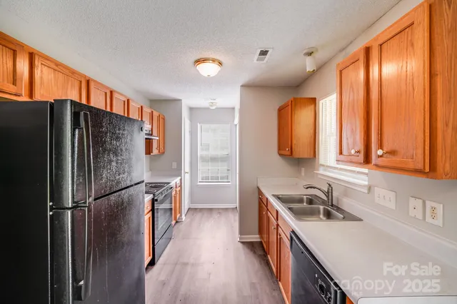 a kitchen with stainless steel appliances granite countertop a refrigerator a sink dishwasher a stove and a dining table with wooden floor