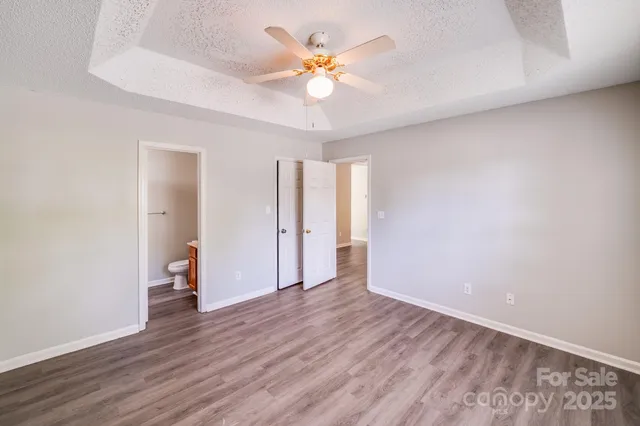 an empty room with wooden floor and a ceiling fan