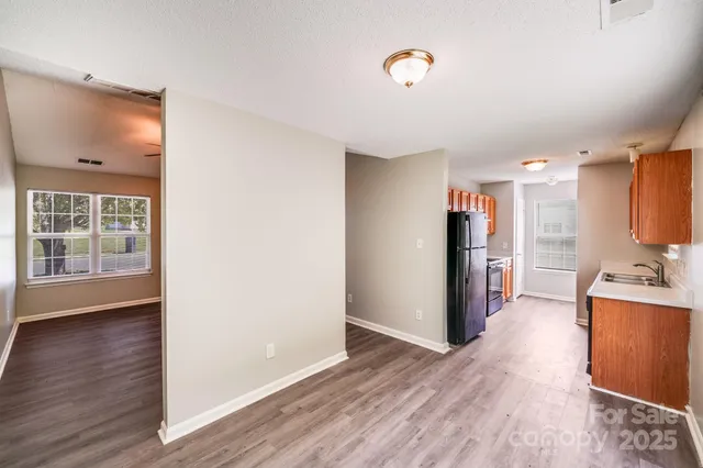 an empty room with wooden floor ceiling fan and windows