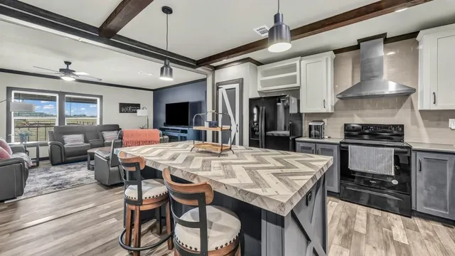 a open kitchen with stainless steel appliances granite countertop a stove a refrigerator a oven a dining table and chairs with wooden floor