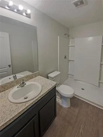 a bathroom with a granite countertop sink a toilet and shower