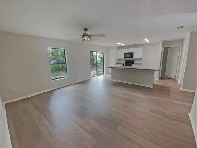 a view of an empty room with a window and wooden floor