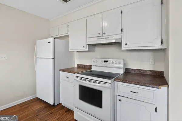 a kitchen with cabinets appliances and wooden floor