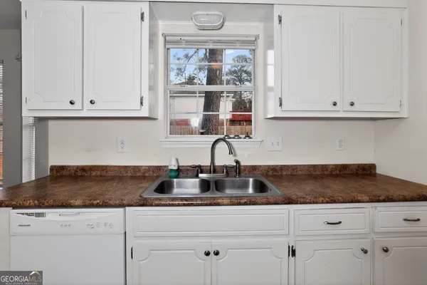 a kitchen with granite countertop white cabinets and a window