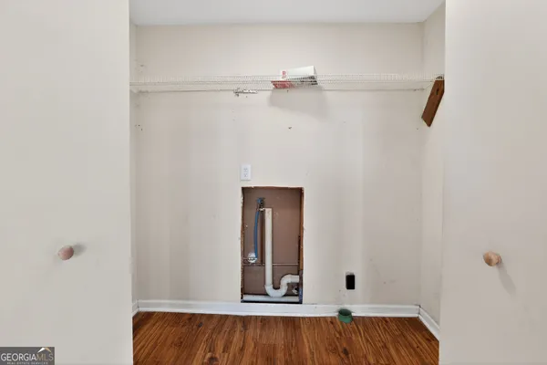 a view of an empty room with wooden floor and mirror