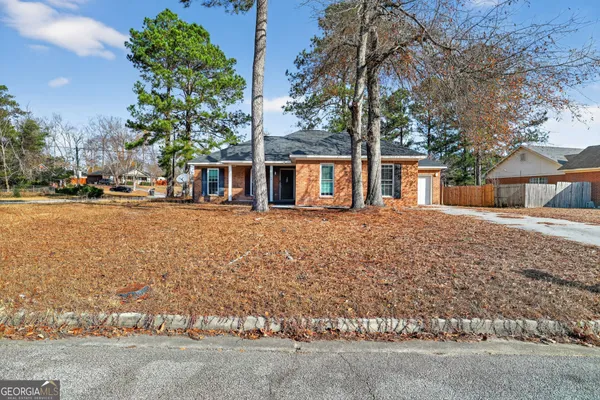front view of house with a yard and trees all around