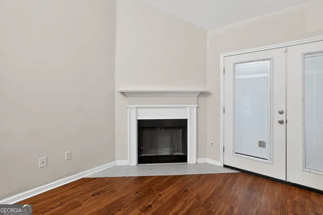 a view of an empty room with wooden floor and a fireplace