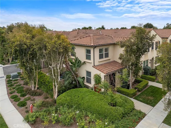 a view of a big yard in front of a brick house with a large tree and plants