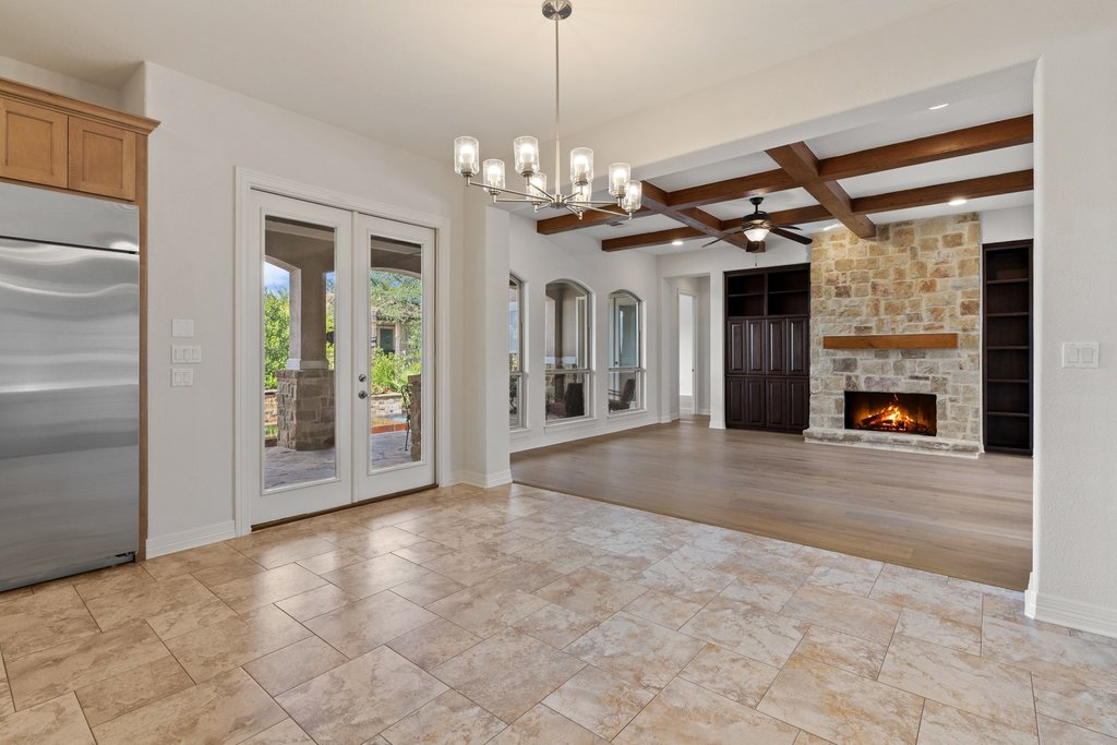 109 Largo Cove Austin, TX 78734 - Photo 13 of 40 French doors open to an inviting patio, complementing the spacious interior with a stone fireplace and exposed beam ceiling.
