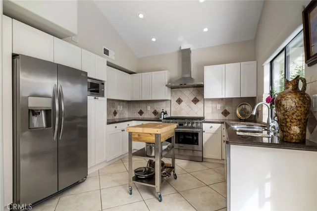 a kitchen with stainless steel appliances granite countertop a refrigerator a stove a sink a dining table and chairs