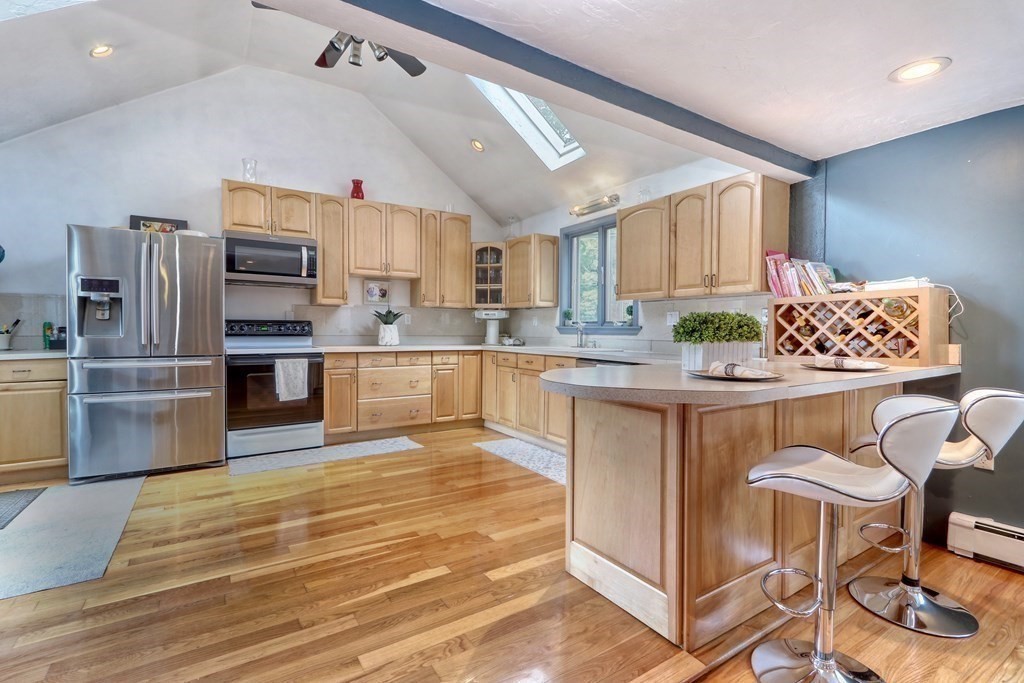 3 Oak Tree Road Dedham, MA 02026 - Photo 8 of 23 a kitchen with stainless steel appliances granite countertop a stove top oven a sink dishwasher a dining table and chairs with wooden floor