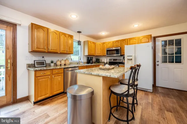 a kitchen with granite countertop wooden floors cabinets and appliances