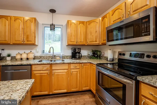 a kitchen with stainless steel appliances granite countertop a stove a sink and a microwave