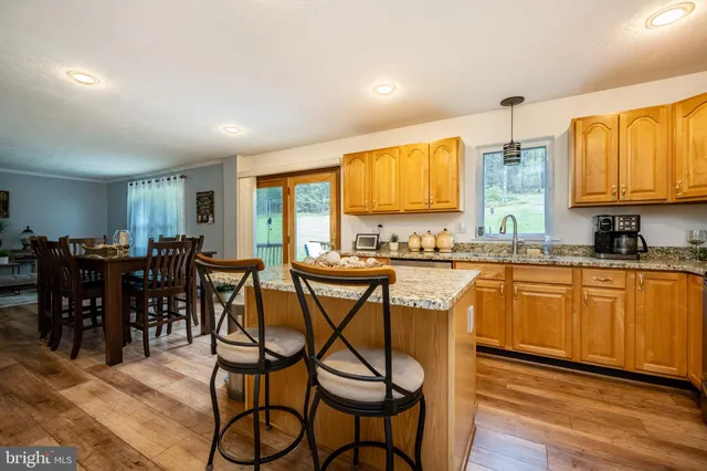 a kitchen with stainless steel appliances granite countertop table chairs sink and window