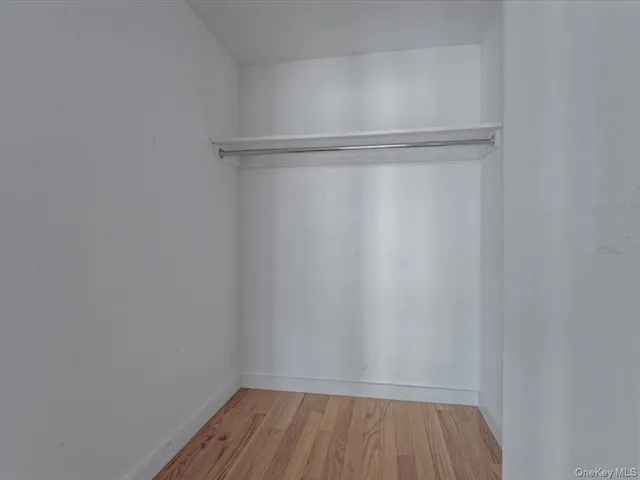 a view of an empty room with wooden floor and closet