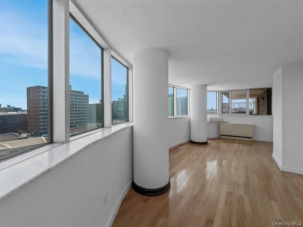 a view of an empty room with a window and wooden floor