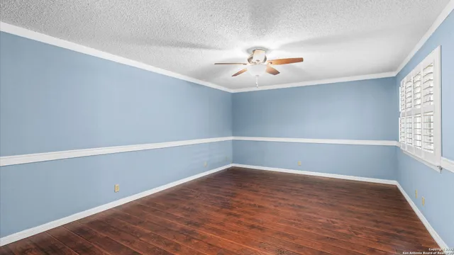 a view of an empty room with a window and wooden floor