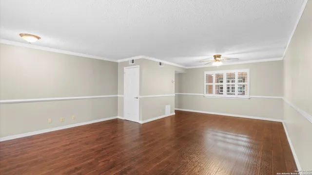 an empty room with wooden floor cabinet and windows