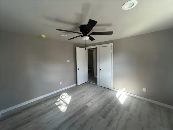 an empty room with wooden floor fan and windows