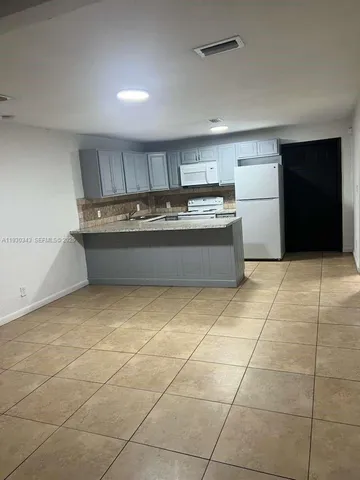 a room with a washing machine and kitchen view